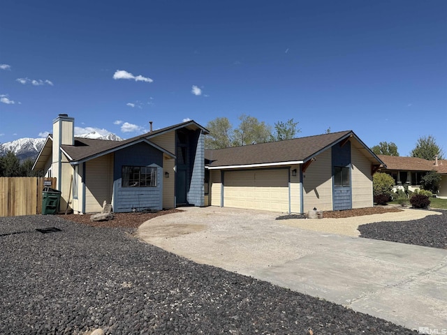 ranch-style home with fence, an attached garage, a chimney, and concrete driveway