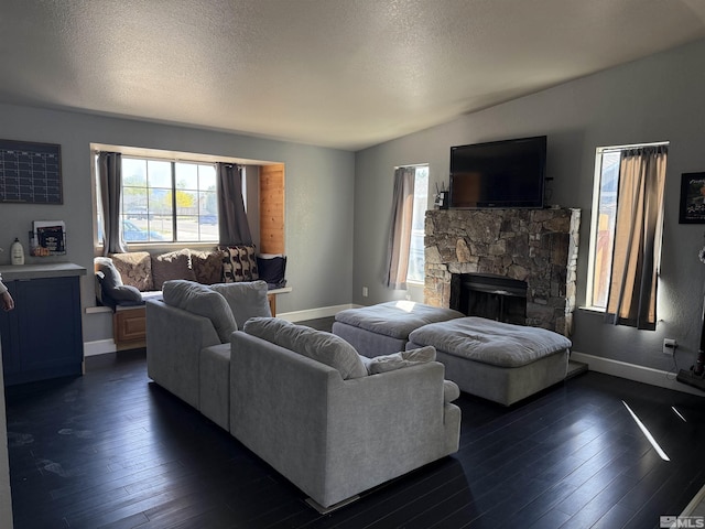 living area featuring baseboards, a stone fireplace, and dark wood-type flooring