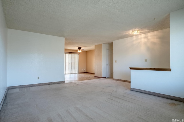 spare room with a textured ceiling, baseboards, light colored carpet, and ceiling fan