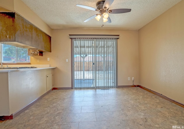 interior space featuring a ceiling fan, a textured ceiling, and baseboards