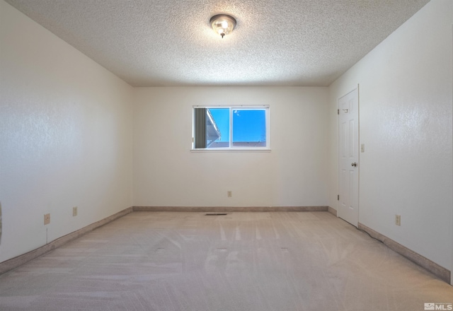 empty room with a textured ceiling, light carpet, and baseboards