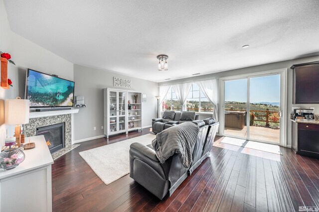 living area with baseboards, a glass covered fireplace, and dark wood finished floors