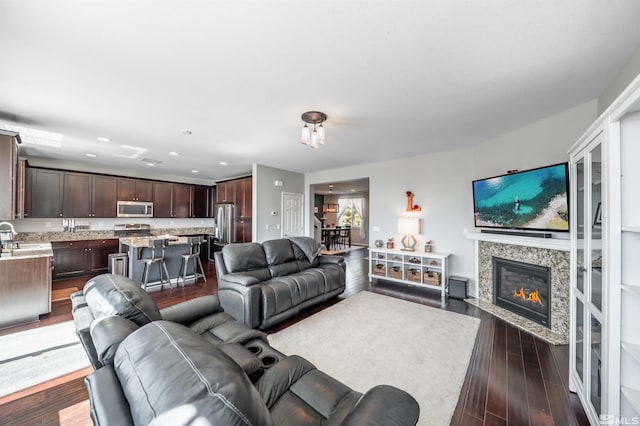 living area featuring a tiled fireplace, recessed lighting, and dark wood-style flooring