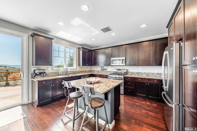 kitchen featuring visible vents, light stone countertops, a sink, dark wood finished floors, and appliances with stainless steel finishes