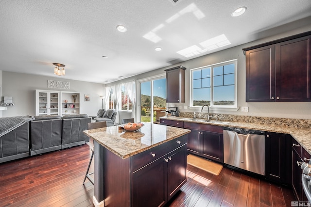 kitchen with dark wood-style flooring, light stone countertops, a sink, dishwasher, and a kitchen island