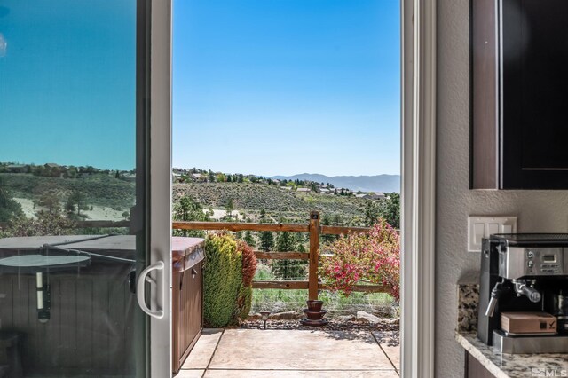 doorway to outside featuring a textured wall, a mountain view, and light tile patterned flooring