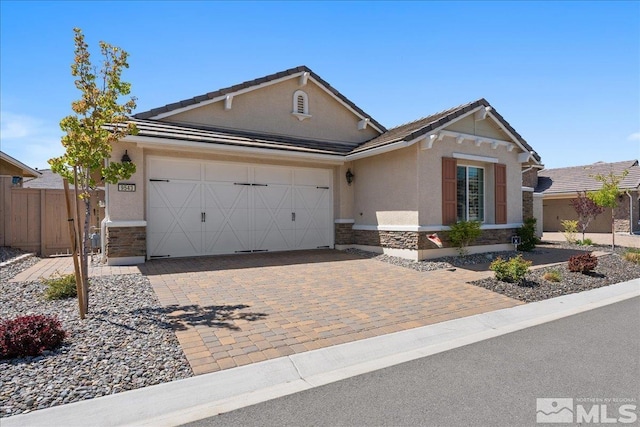 ranch-style home with decorative driveway, fence, an attached garage, stone siding, and stucco siding