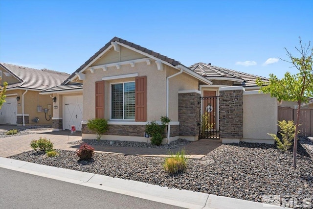 view of front of house with fence, an attached garage, a tile roof, stone siding, and a gate