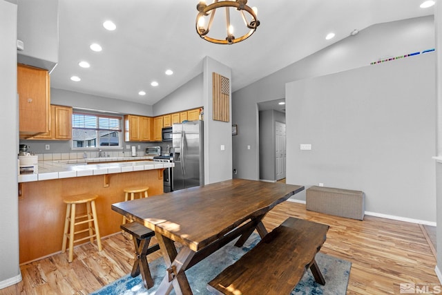 dining room with an inviting chandelier, light wood-style floors, vaulted ceiling, and recessed lighting