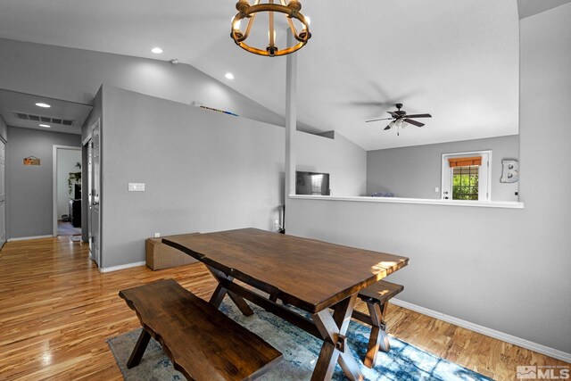 dining area featuring baseboards, vaulted ceiling, light wood finished floors, and ceiling fan with notable chandelier