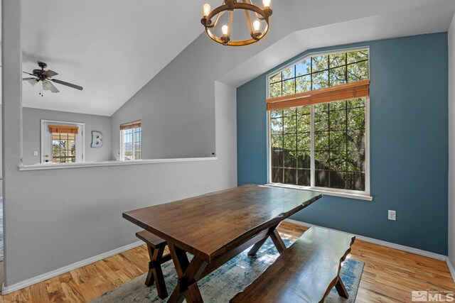 dining room featuring wood finished floors, baseboards, ceiling fan with notable chandelier, and lofted ceiling