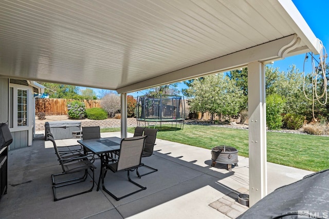 view of patio with a fenced backyard, a trampoline, an outdoor fire pit, and outdoor dining space