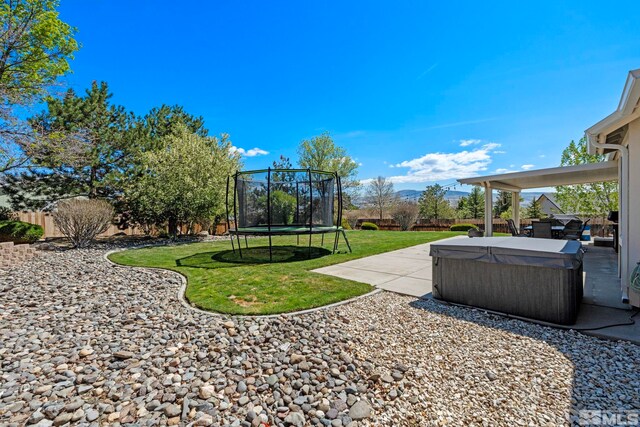 view of yard with a hot tub, a fenced backyard, a patio area, and a trampoline