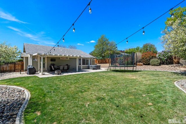 back of property featuring a fenced backyard, a trampoline, a lawn, and a patio area