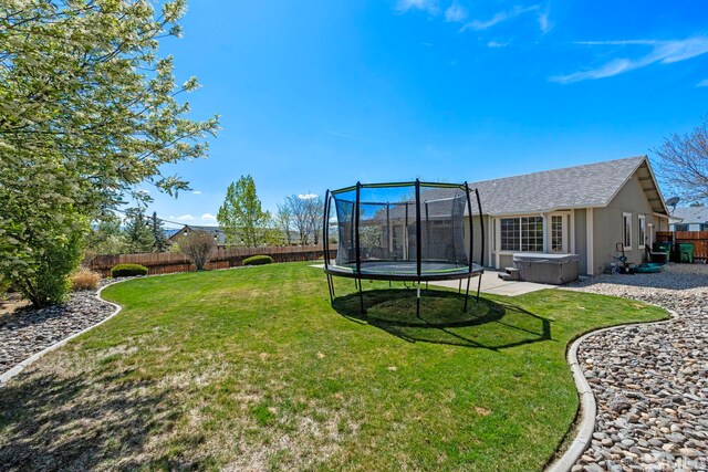 view of yard featuring a fenced backyard, a trampoline, and a hot tub