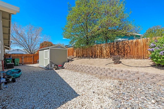 view of yard featuring a storage unit, a fenced backyard, central air condition unit, and an outdoor structure