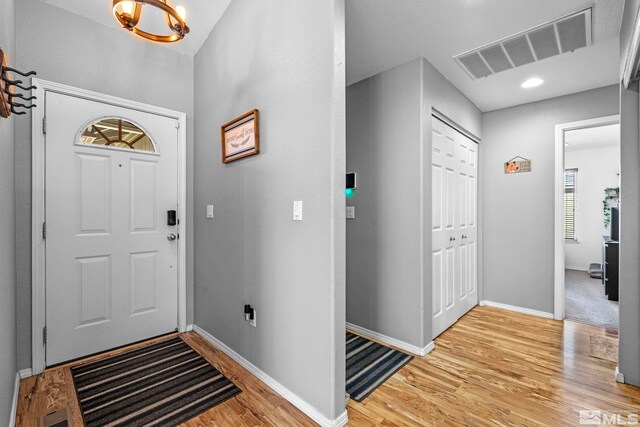 entrance foyer with baseboards, a notable chandelier, light wood finished floors, and visible vents