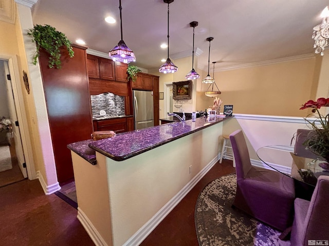 kitchen featuring freestanding refrigerator, a peninsula, baseboards, and pendant lighting