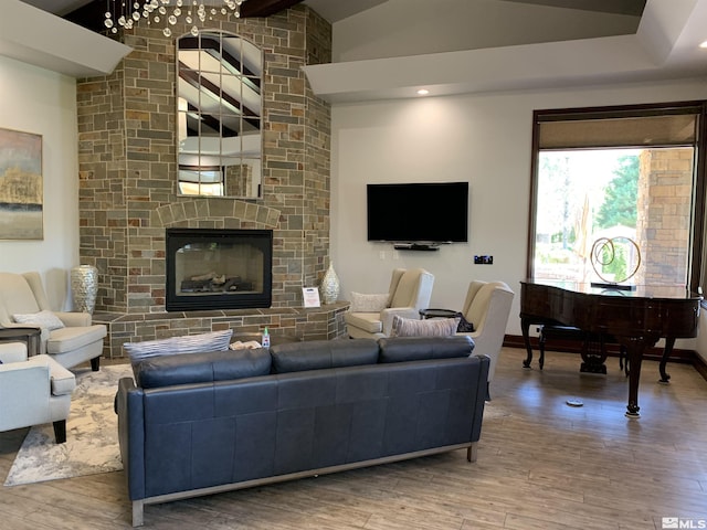 living room featuring a large fireplace, baseboards, wood finished floors, and lofted ceiling
