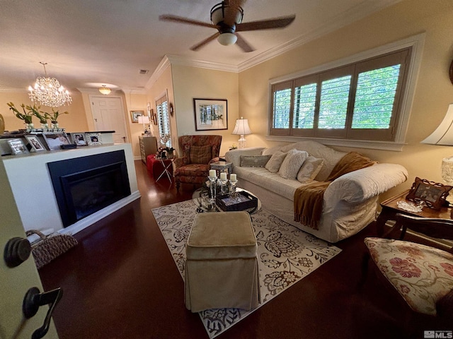 living area with crown molding, a glass covered fireplace, wood finished floors, and ceiling fan with notable chandelier