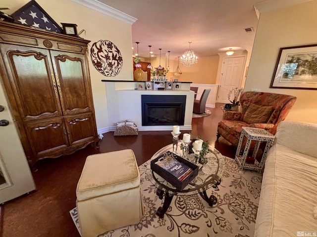 living area featuring visible vents, crown molding, a glass covered fireplace, baseboards, and a chandelier