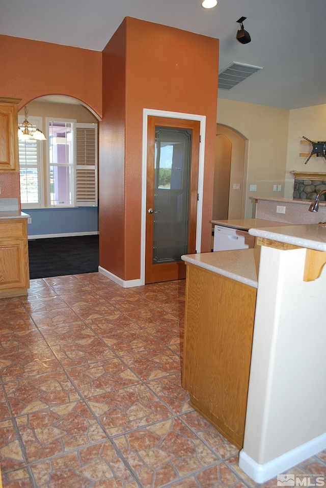 kitchen with baseboards, arched walkways, a healthy amount of sunlight, and light countertops