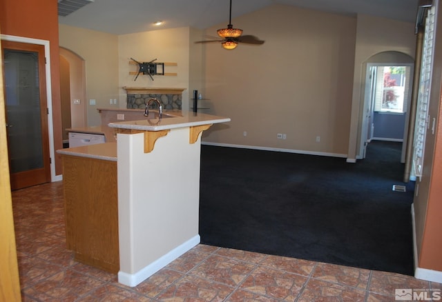 kitchen featuring ceiling fan, a breakfast bar area, visible vents, arched walkways, and carpet