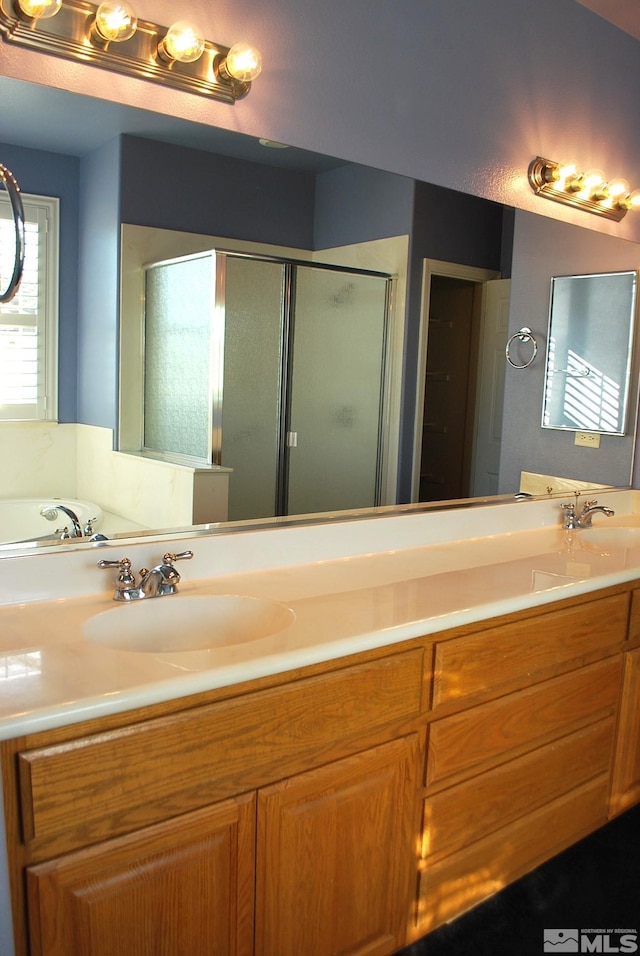 bathroom with a sink, a shower stall, and double vanity