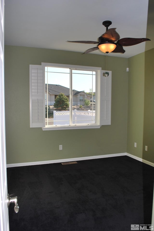 empty room with baseboards, a ceiling fan, and dark carpet