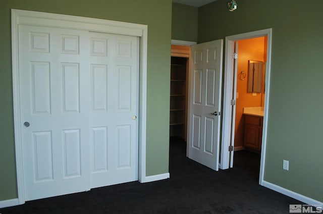 unfurnished bedroom with baseboards, dark carpet, and a closet