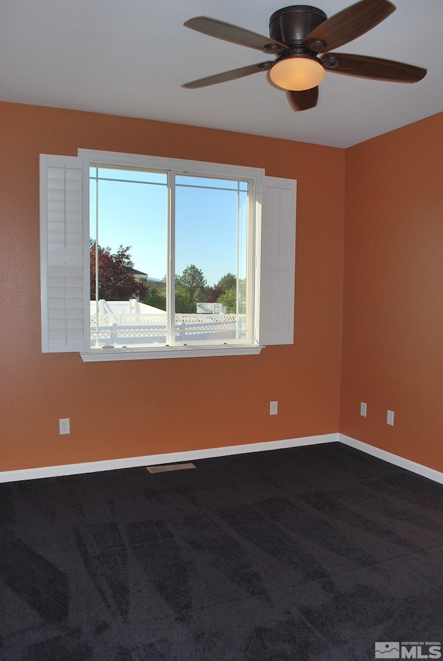 spare room featuring baseboards, ceiling fan, and dark carpet