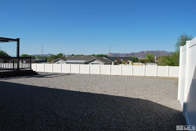 view of yard with fence and a deck with mountain view