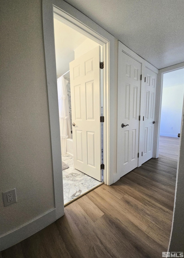 hall with dark wood-style flooring and a textured ceiling