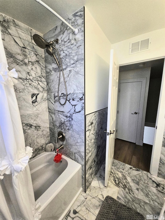 bathroom featuring shower / tub combo with curtain, marble look tile flooring, a textured ceiling, and tile walls