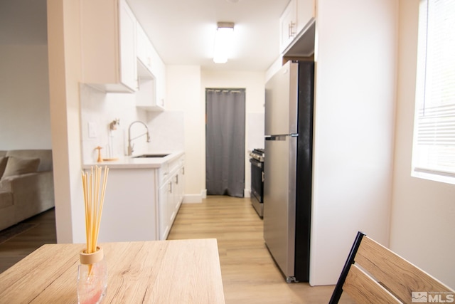 kitchen featuring a sink, appliances with stainless steel finishes, light countertops, white cabinets, and light wood finished floors
