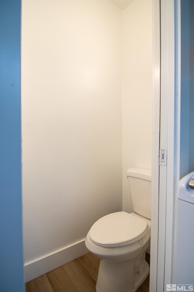 bathroom with washer / dryer, toilet, baseboards, and wood finished floors