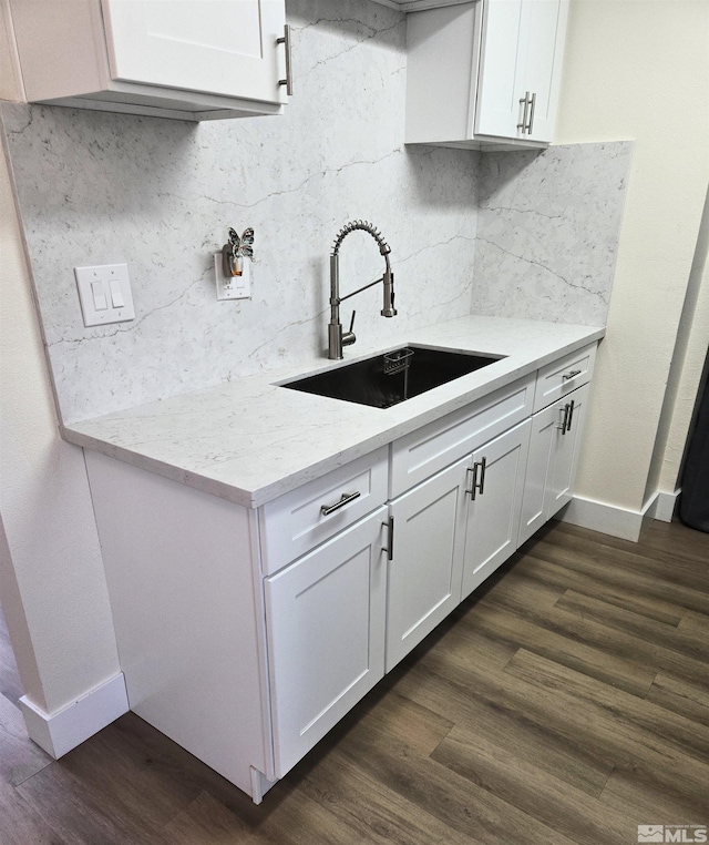 kitchen with a sink, white cabinetry, baseboards, and tasteful backsplash