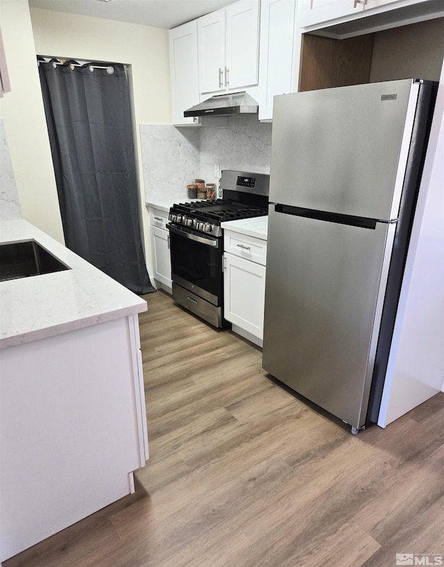 kitchen featuring stainless steel appliances, under cabinet range hood, light wood finished floors, and white cabinetry