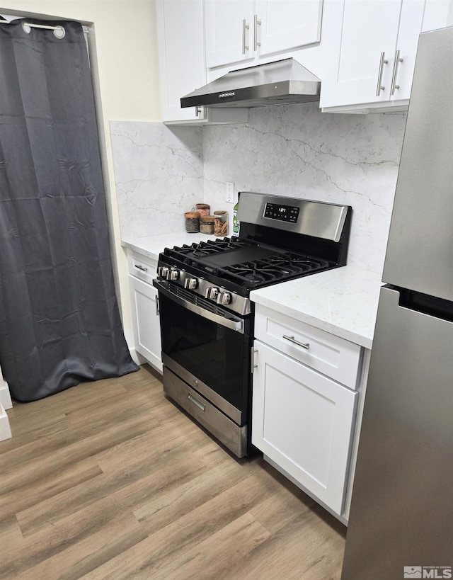 kitchen featuring under cabinet range hood, appliances with stainless steel finishes, light wood finished floors, and white cabinets