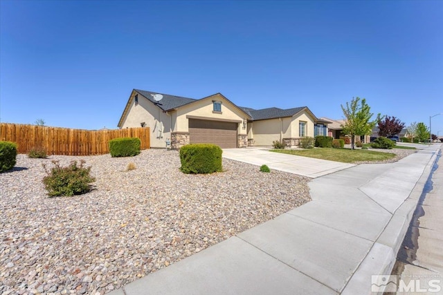 ranch-style home featuring fence, an attached garage, stone siding, stucco siding, and concrete driveway