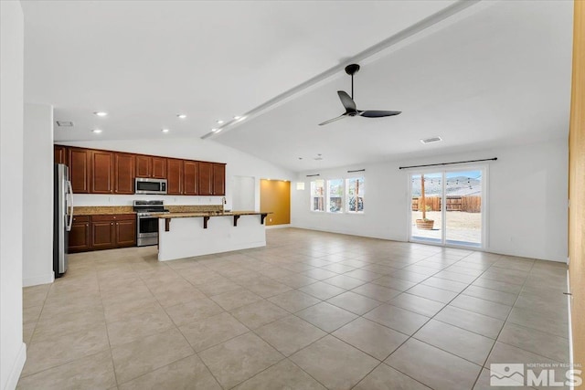 kitchen featuring ceiling fan, appliances with stainless steel finishes, a breakfast bar, open floor plan, and vaulted ceiling
