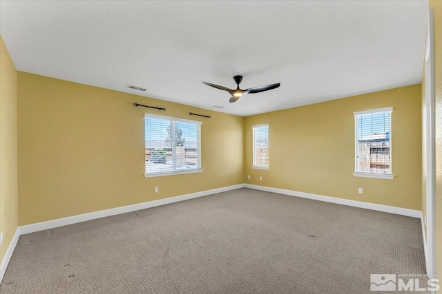 empty room featuring baseboards, plenty of natural light, a ceiling fan, and visible vents