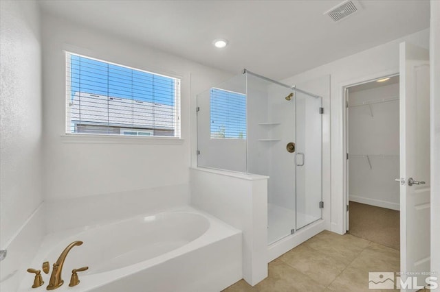 bathroom with visible vents, a walk in closet, a garden tub, and a stall shower
