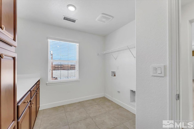 washroom with cabinet space, light tile patterned flooring, washer hookup, baseboards, and visible vents