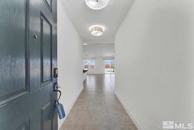 hallway featuring light tile patterned floors and baseboards