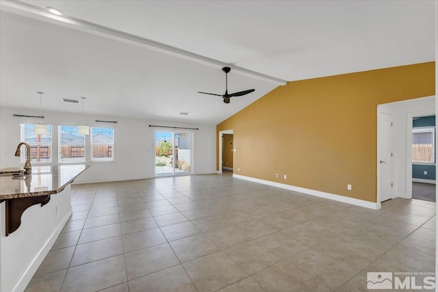 unfurnished living room with baseboards, light tile patterned floors, a ceiling fan, and a sink