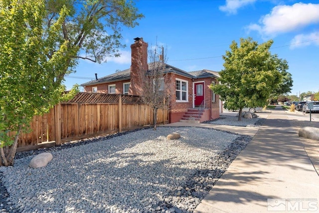 view of front of property with brick siding, fence, and a chimney