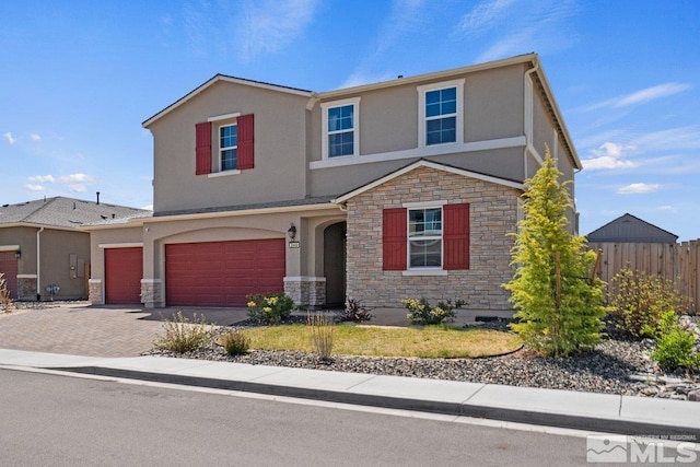 traditional home featuring fence, stucco siding, and stone siding