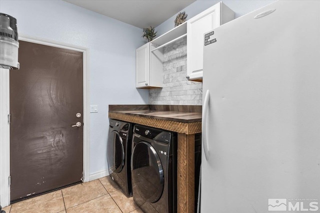 laundry area with washer and dryer, light tile patterned floors, and cabinet space