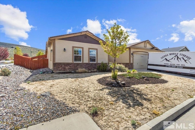 ranch-style house with a garage, fence, stucco siding, and stone siding